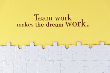 Business motivational quote - Team work makes the dream work. On yellow background of white jig saw puzzle missing pieces. Success team work concept.