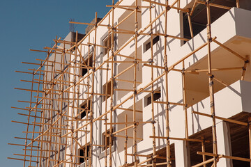 Construction building houses made of stone and sandstone using scaffolding in Egypt, blue sky