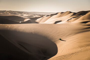 Dune buggying in sand dunes at sunset in the desert at Huacachina, Ica Region, Peru, South America