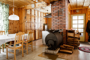 Bullerjan home wood burn stove heating device in wooden cottage home interior, with stack of...