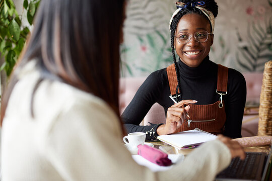 Two Multicultural Female Students Sitting In A Cafe And Studying For An Exam. The Lifestyle Of A Student.