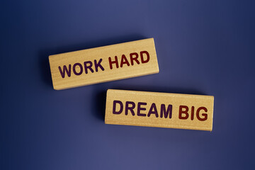 The words Work hard dream big is written on a wooden blocks on a beautiful dark blue background. Concept text