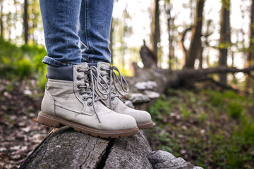 Tourist with hiking boot standing on tree trunk in forest. Active lifestyle in nature. Leather ankle boots