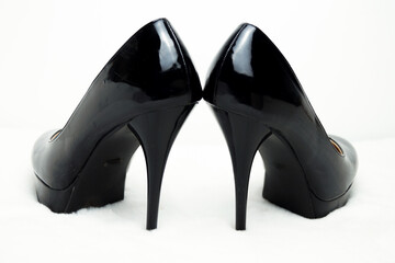 Black high-heeled shoes on a white fur rug.