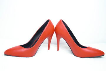 Red high-heeled shoes on a white fur rug.