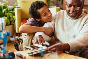 A grandad and grandson making a robot together at home. Education in robotics and electronics.