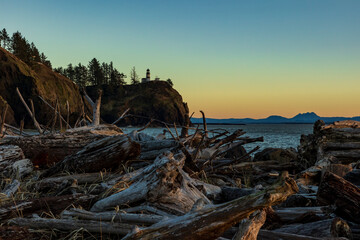 Sunset in Cape Disappointment state park.dramatic sun setting in Cape Disappointment rocky cliffs and light house with massive drift wood logs on the bay area.