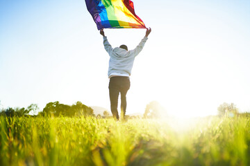 Unrecognizable man running with LGBT flag in countryside