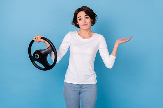 Photo of pretty positive lady failing driving exam hold steering wheel shrug shoulder isolated on blue color background