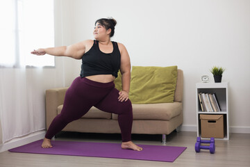 Fototapeta na wymiar Attractive asian young fitness woman plus size stretching arms warming up before doing yoga at home. Beautiful smiling Female wearing sportswear exercise training yoga in living room.