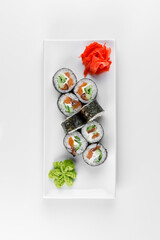 Sushi roll Syake Maki with red fish, cucumber and rice in nori seaweed. Plate on a white background.