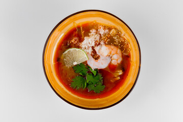 Hot soup with shrimp, rice, parsley and lime. White background and deep plate.