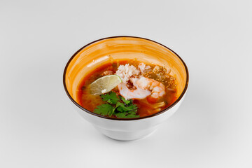 Hot soup with shrimp, rice, parsley and lime. White background and deep plate.