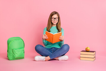 Photo of smart girl wear turquoise sweater holding school supplies reading book isolated pink color...