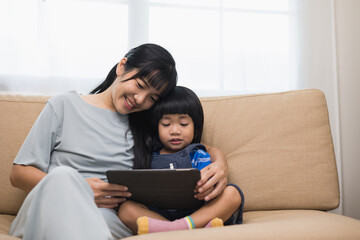 Happy asian family mother and  son using tablet for education. Little boy watching funny social media.  Mom with kid using tablet video call to father.