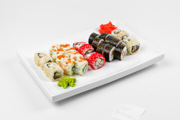 Set of different sushi rolls with rice, fish, cucumbers, wasabi, ginger, caviar and sesame. Large white plate on a white background. Lots of sushi in one dish.