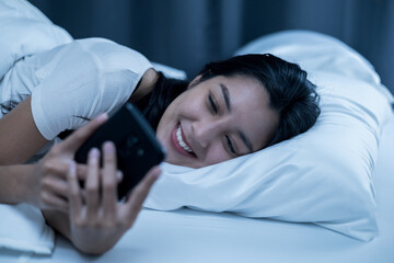 Pretty asian woman using smart phone on bed to social media at home. Lifestyle of young beautiful female using mobile phone to network internet online before sleep.