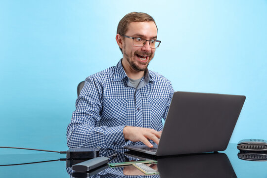 Portrait of man in glasses and checkered shirt, computer geek, programmer isolated over blue background