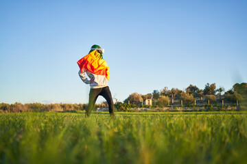 Person with LGBT flag and VR goggles in green field