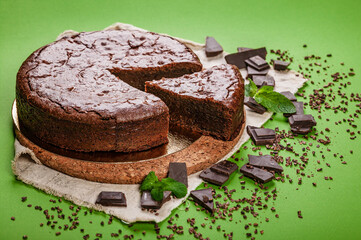 Classic chocolate brownie cake on a green background. Homemade delicious pastries. Sweet dessert. Copy space