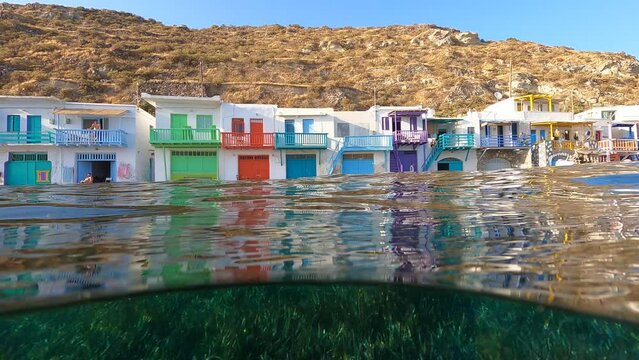 Underwater split video of famous traditional fisherman settlement of Klima with colourful boat houses called sirmata, Milos island, Cyclades, Greece