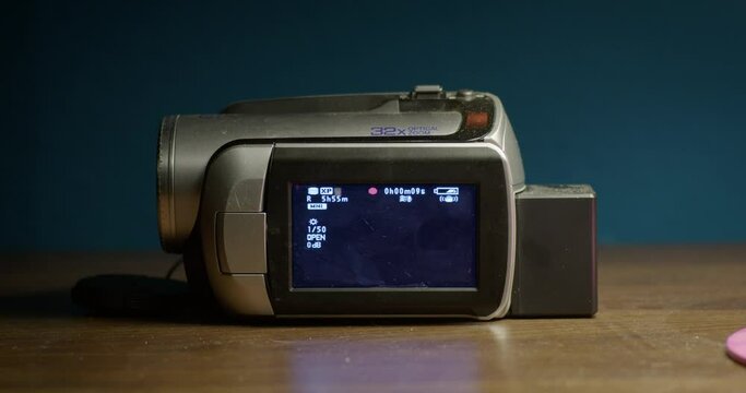 old mini dv camcorder with opened display on wooden table showing the red record screen, nice music video footage or mock up. 
