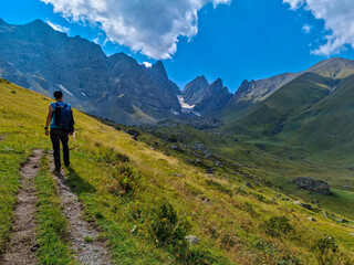 A man walking on a hiking trail with a view on the sharp mountain peaks of the Chaukhi massif in the Greater Caucasus Mountain Range in Georgia, Kazbegi Region. Remedy, Wanderlust.Georgian Dolomites