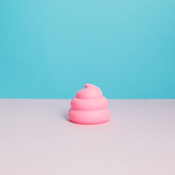 Pink poop emoticon on pastel blue and white background. Funny concept.