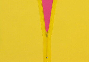 Yellow zipper unzipped half way showing violet color under a yellow background. © Ivan