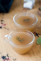 Homemade bone broth in a mugs on a wooden table. The concept of healthy food. 