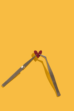 Red heart and tweezers on a yellow background. Valentine day concept. Study test and love experiment. Broken heart idea. Flat lay with copy space.