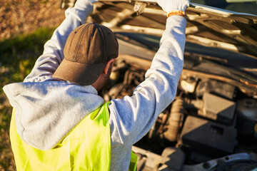 Faceless man checking engine under hood