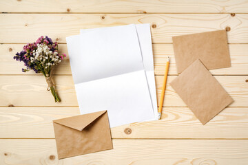 Flowers, blank paper and envelope on a table top