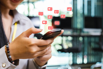Businesswoman using smartphone with notification social media icons, internet digital marketing concept.