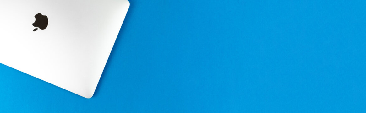 Apple Macbook on bright blue table background, banner with copy space. Business and office concept, top view, flat lay photo