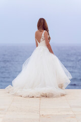 Fototapeta na wymiar Brunette bride in white dress looking at the sea