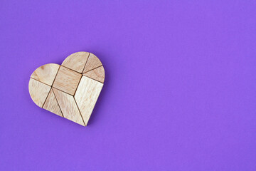 Wooden heart puzzle on purple background