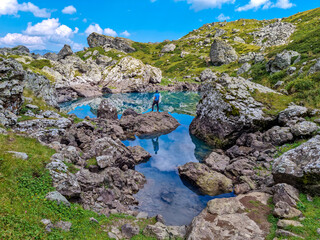 A man enjoying the Colorful Abudelauri mountain lakes in the Greater Caucasus Mountain Range in Georgia,Kazbegi Region. Trekking and outdoor travel.Alpine pastures.Backpacking and trekking.Green lake