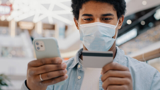 African american man client customer in medical mask entering banking credit card data in phone mobile app pays purchase goods online services Internet payment easy financial transfers virtual money