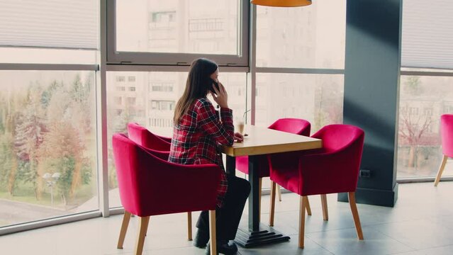 Young Business Woman In Red Jacket Is Sitting At Fancy Table In Cafe And Talking Cell Phone, Making Arrangement, Waiting For Meeting With Client, Zoom In, Slow Motion.