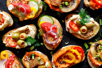 Colorful vegetarian sandwiches with hummus and vegetables with fresh herbs and spices, top view