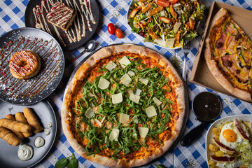 Pizza dinner. Flat lay of various types of Italian pizza and desserts on restaurant table, top view, wide composition.