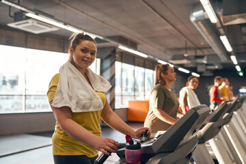 Fototapeta na wymiar Smiling girl run on treadmill and look at camera