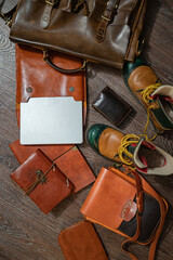 A set of vintage brown leather every day use man accessorys: a briefcase, messenger bag, tramp shoes, a purse, notebook and a notepad with a handmade leather binding, and a laptop. Top view (flat-lay)
