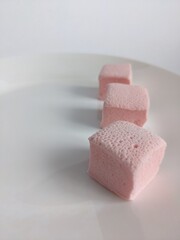 tree cubes of pink craft marshmallow on the white plate