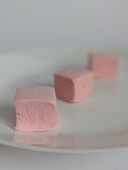 tree cubes of pink craft marshmallow on the white plate