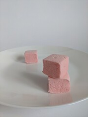 tree cubes of pink craft marshmallow on the white plate
