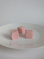 tree cubes of pink craft marshmallow on the white plate