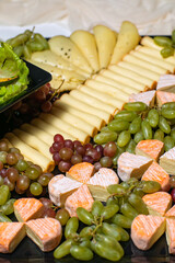 various types of cheese on wooden cutting board, top view
