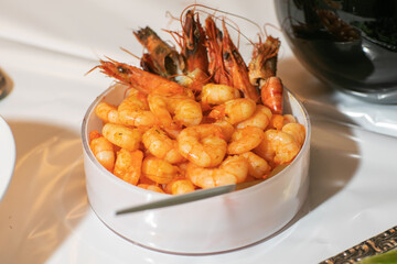 delicious deep fried breaded shrimps served with lime wedges and coriander leaves on white plate on wooden table, copy space for text, view from above